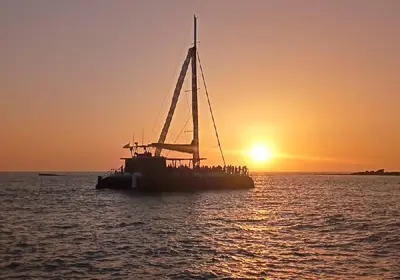 a boat with people on it in the water at sunset at Dúplex Chiclana Centro con Terraza y Parking By Chiclana Dreams in Chiclana de la Frontera