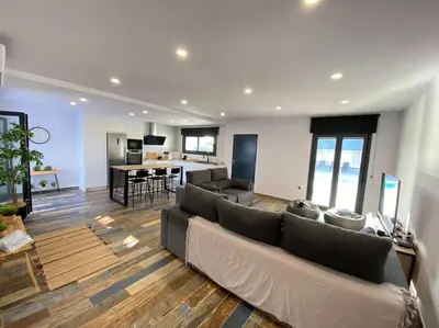 a large living room with a couch and a kitchen at Villa Romance in Chipiona
