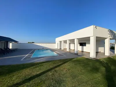 a white building with a swimming pool in a yard at Villa Romance in Chipiona