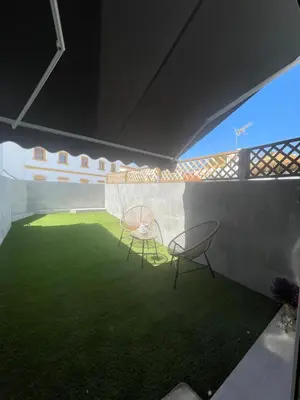 two chairs and a table in a room with grass at Apartamentos Corredera 4 in Arcos de la Frontera
