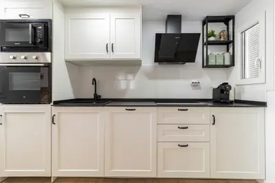a kitchen with white cabinets and black appliances at Allo Apartments Morenos V Centro Gran Terraza in Jerez de la Frontera