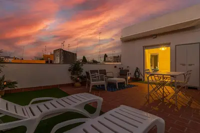 a patio with a table and chairs and a sunset at Allo Apartments Morenos V Centro Gran Terraza in Jerez de la Frontera