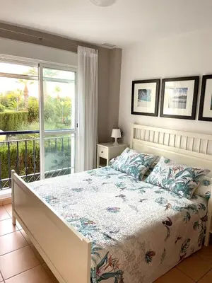 a bedroom with a large bed and a balcony at Oasis Flamencos Golf in Sanlúcar de Barrameda