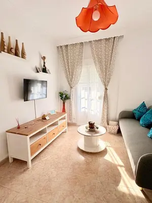 a living room with a ceiling fan and a room with a television at El rincón de Nai in Chiclana de la Frontera