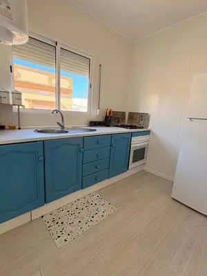a kitchen with blue cabinets and a sink and a refrigerator at El rincón de Nai in Chiclana de la Frontera