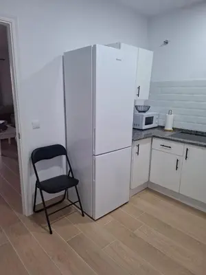 a black chair in a kitchen with a refrigerator at Apartamento Las Arenas in Chiclana de la Frontera