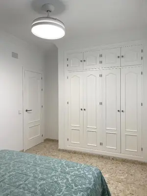 a white bedroom with white cabinets and a bed at Casa Elena in Conil de la Frontera