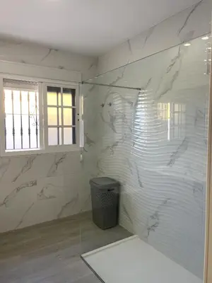 a bathroom with a shower with a glass wall at Casa Elena in Conil de la Frontera