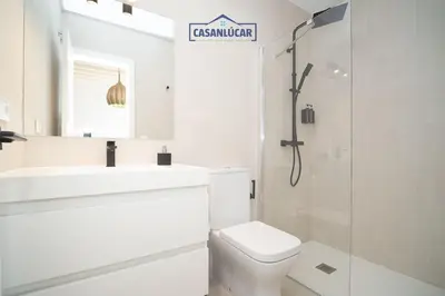 a white bathroom with a toilet and a sink at Sanlucar Centro - Apartamento 1 in Sanlúcar de Barrameda