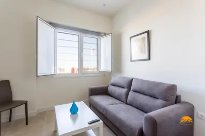 a living room with a couch and two windows at Delfin Azul 2 FREE PARKING by Cadiz Time in Cádiz