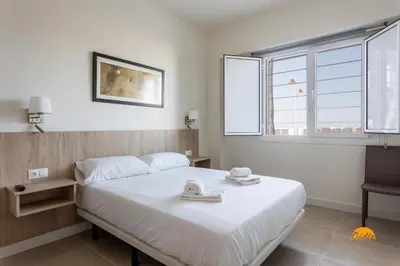 a bedroom with a bed and a chair and windows at Delfin Azul 2 FREE PARKING by Cadiz Time in Cádiz