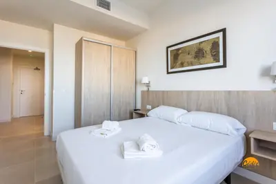 a bedroom with a large white bed with two towels at Delfin Azul 2 FREE PARKING by Cadiz Time in Cádiz