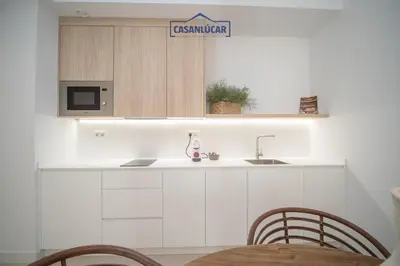 a kitchen with a sink and a microwave and a table at Sanlucar Centro - Apartamento 2 in Sanlúcar de Barrameda