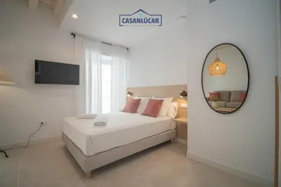 a bedroom with a white bed and a mirror at Sanlucar Centro - Apartamento 2 in Sanlúcar de Barrameda