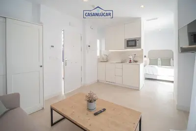 a white living room with a table and a bedroom at Sanlucar Centro - Apartamento 5 in Sanlúcar de Barrameda
