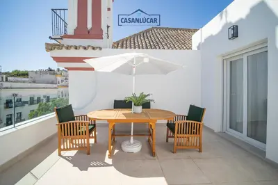 a table with chairs and an umbrella on a balcony at Sanlucar Centro - Apartamento 5 in Sanlúcar de Barrameda