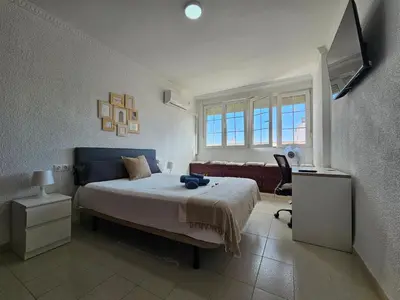 a bedroom with a bed and a couch and a television at Apartamento Granja - a 5 min de la playa in Cádiz