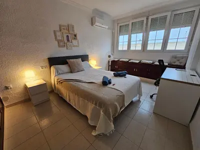 a bedroom with a bed and a desk and windows at Apartamento Granja - a 5 min de la playa in Cádiz