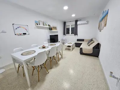 a living room with a table and chairs and a couch at Apartamento Granja - a 5 min de la playa in Cádiz