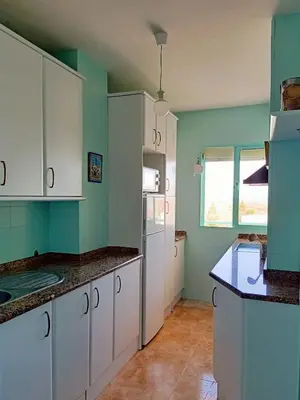 a kitchen with green walls and white cabinets at Azvalia Puerto Príncipe 2 in El Puerto de Santa María