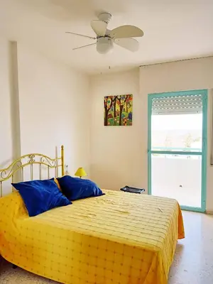 a bedroom with a yellow bed with a ceiling fan at Azvalia Puerto Príncipe 2 in El Puerto de Santa María