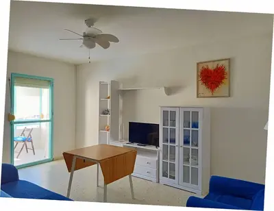 a living room with a table and a tv at Azvalia Puerto Príncipe 2 in El Puerto de Santa María