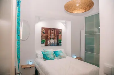 a white bedroom with a bed with blue pillows at Apartamento en pleno centro historico in Cádiz