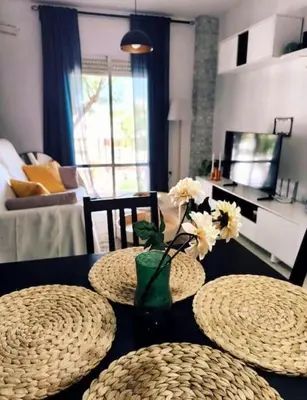 a table with two plates and a vase with flowers on it at Apartamento V CENTENARIO BEACH Sanlúcar in Sanlúcar de Barrameda