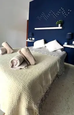 a bedroom with a bed with a blue wall at Apartamento V CENTENARIO BEACH Sanlúcar in Sanlúcar de Barrameda