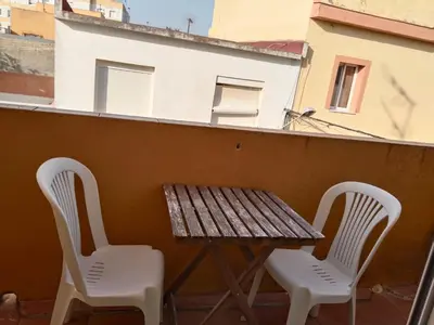 two chairs and a wooden table on a balcony at Bienvenidos Villa Roki Para información seis3tres 0nueve 0nueve veinte in El Puerto de Santa María