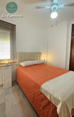 a bedroom with a bed with an orange comforter at La Especiería relax by Sanlúcar Housing in Sanlúcar de Barrameda