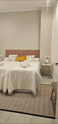 a bedroom with two beds with white sheets and a table at el 2 de Flamenco BajoA in Cádiz