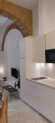 a kitchen with white cabinets and a table in a room at el 2 de Flamenco BajoA in Cádiz