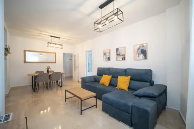 a living room with a blue couch and a table at Piso en el Barrio Alto in Sanlúcar de Barrameda
