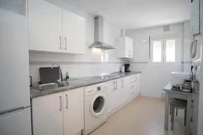a white kitchen with a sink and a washing machine at Piso en el Barrio Alto in Sanlúcar de Barrameda