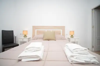 a white bedroom with a large white bed with towels on it at Piso en el Barrio Alto in Sanlúcar de Barrameda
