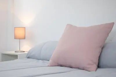 a pink pillow sitting on a bed next to a lamp at Piso en el Barrio Alto in Sanlúcar de Barrameda