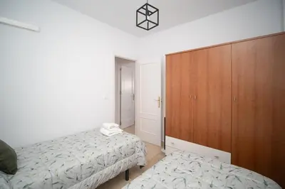 a bedroom with two beds and a wooden cabinet at Piso en el Barrio Alto in Sanlúcar de Barrameda