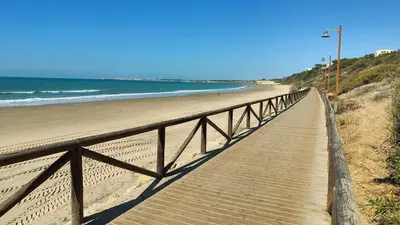 a wooden boardwalk leading down to the beach at Pantoque Sani Ideal para familias in El Puerto de Santa María