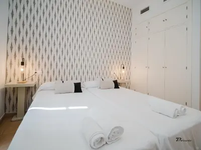 a white bedroom with a large white bed with two towels at Sibs Sanlucar Fariñas 11 Edif Historico Renovado Ideal Parejas in Sanlúcar de Barrameda