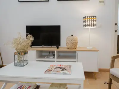 a living room with a tv on a white table at Sibs Sanlucar Fariñas 11 Edif Historico Renovado Ideal Parejas in Sanlúcar de Barrameda