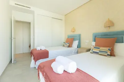 a bedroom with two beds with white and orange at Costa Ballena Deluxe Seafront by Valcambre in Cádiz