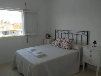 a white bedroom with a bed with towels on it at Piso IBERIAN PREMIUM in Sanlúcar de Barrameda