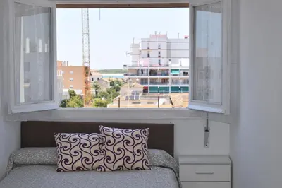 a window in a room with a couch and a pillow at Piso IBERIAN PREMIUM in Sanlúcar de Barrameda