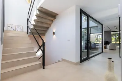 a staircase in a house with white walls and glass doors at Villa Gatán in Chiclana de la Frontera