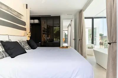 a bedroom with a large white bed and a bathroom at Villa Gatán in Chiclana de la Frontera
