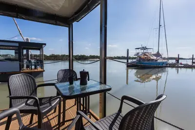 a table and chairs on a dock with a boat at Azvalia Luxury Casa Barco New York and Texas-Unique Houseboat Experience in El Puerto de Santa María