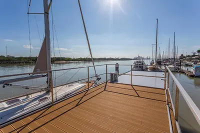 a boat with a wooden deck on the water at Azvalia Luxury Casa Barco New York and Texas-Unique Houseboat Experience in El Puerto de Santa María