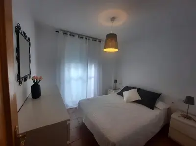 a bedroom with a bed and a table with flowers on it at apartamento Atlanta in Chipiona