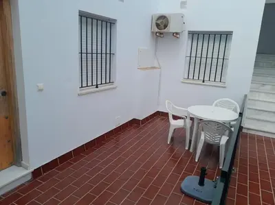 a table and chairs in a room with a white wall at apartamento Atlanta in Chipiona